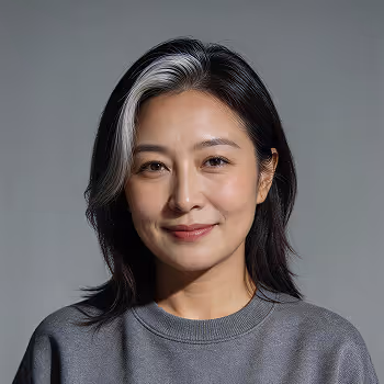 Portrait of a smiling Asian woman with black hair and a gray streak, wearing a gray sweater.