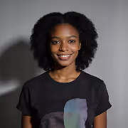 Smiling young Black woman with natural afro hair wearing a black t-shirt against gray background.
