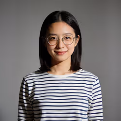 Smiling woman with glasses and straight black hair wearing a striped white and navy blue shirt.